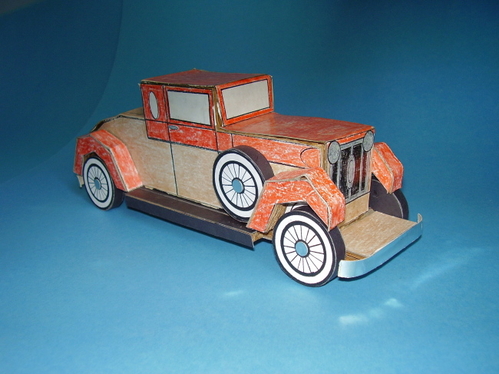 Solid corrugated model of a 1920's car.
16 profile shaped layers of corrugated cardboard, glued together side by side into a solid body, four layers for each fender, two for each wheel.  Car covered with crayon colored paper.

