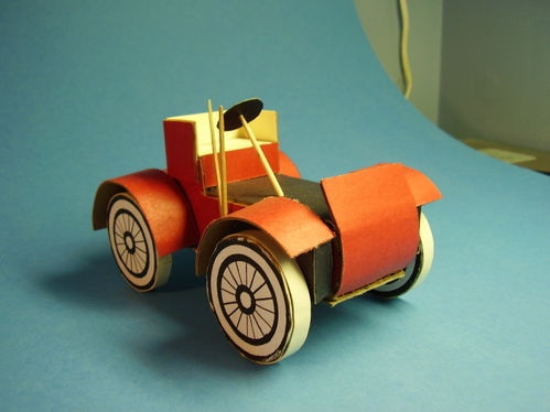 1902 Runabout.
12 layers of corrugated cardboard, cut to the body's profile shape, and glued together side by side to form a solid body.  Sheet cardboard and posterboard fenders; posterboard surface covering.
