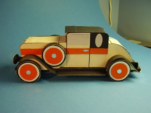 1920's coupe.
16 layers of corrugated cardboard, cut to the car's profile and glued side by side, form a solid body.  Sheet cardboard and posterboard for fenders; posterboard for surface covering.
